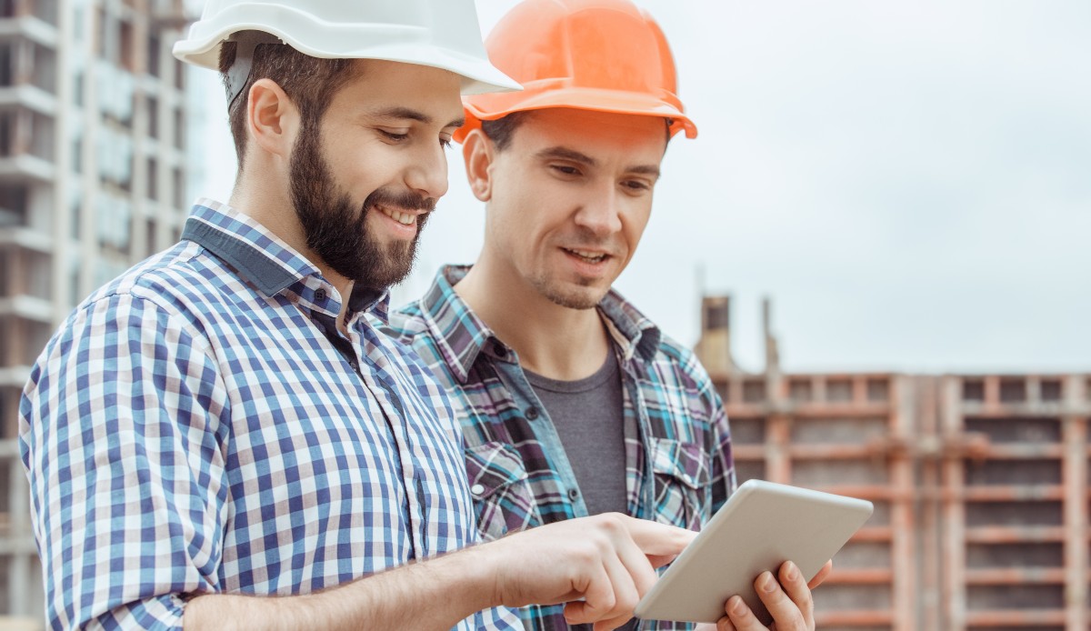 Two construction workers discussing a project over a tablet